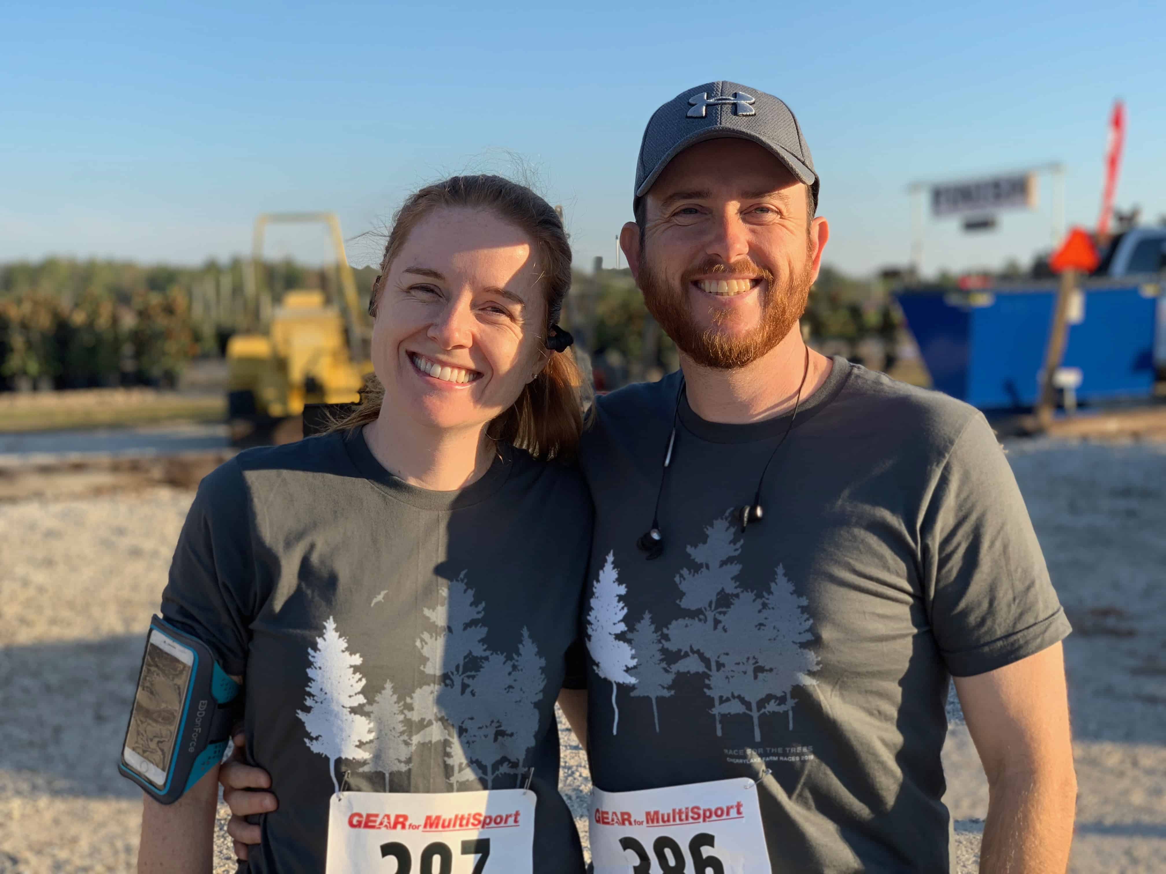 A couple in matching gray shirts smile together after a race.