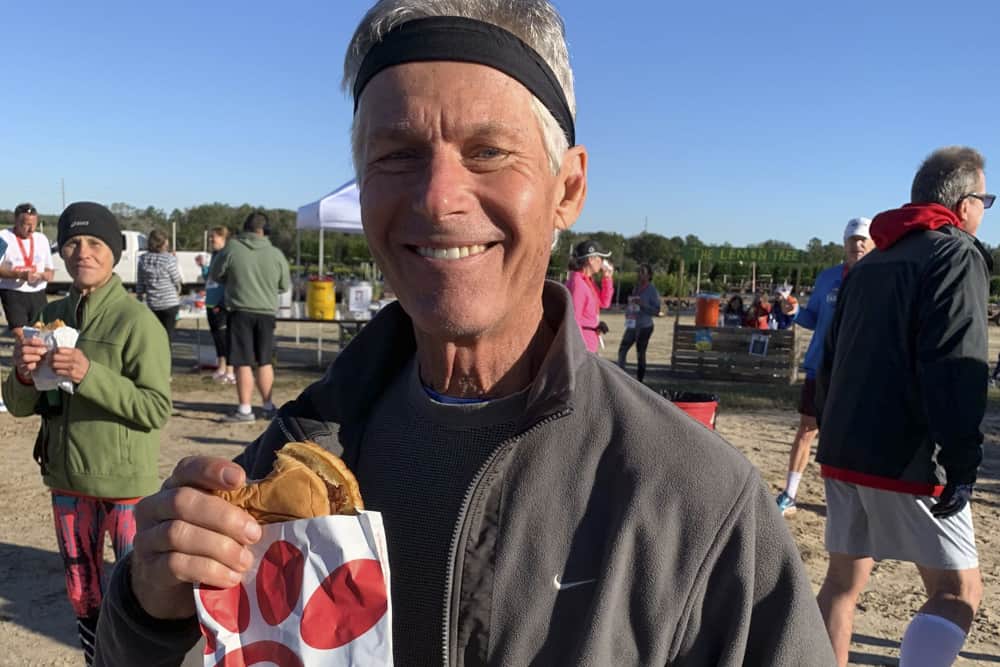 Male runner holding a Chick-Fil-A Sandwich after the race.